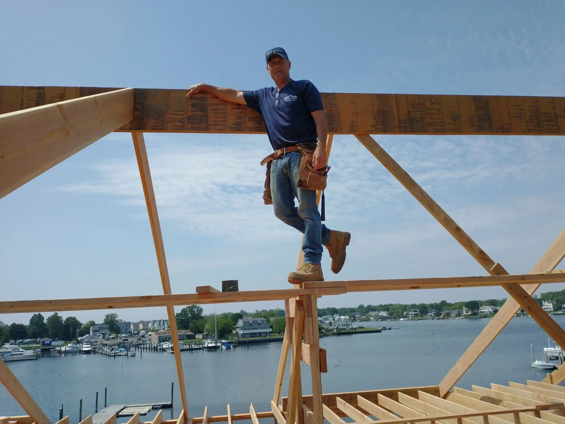 Carpenter standing on roof frame near water
